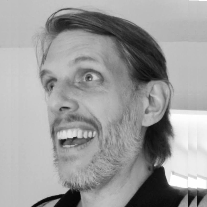 A black-and-white picture of a *very* handsome man, who is grinning.